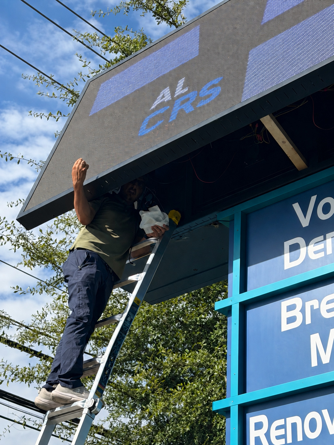 Technician working on an elevated outdoor LED sign