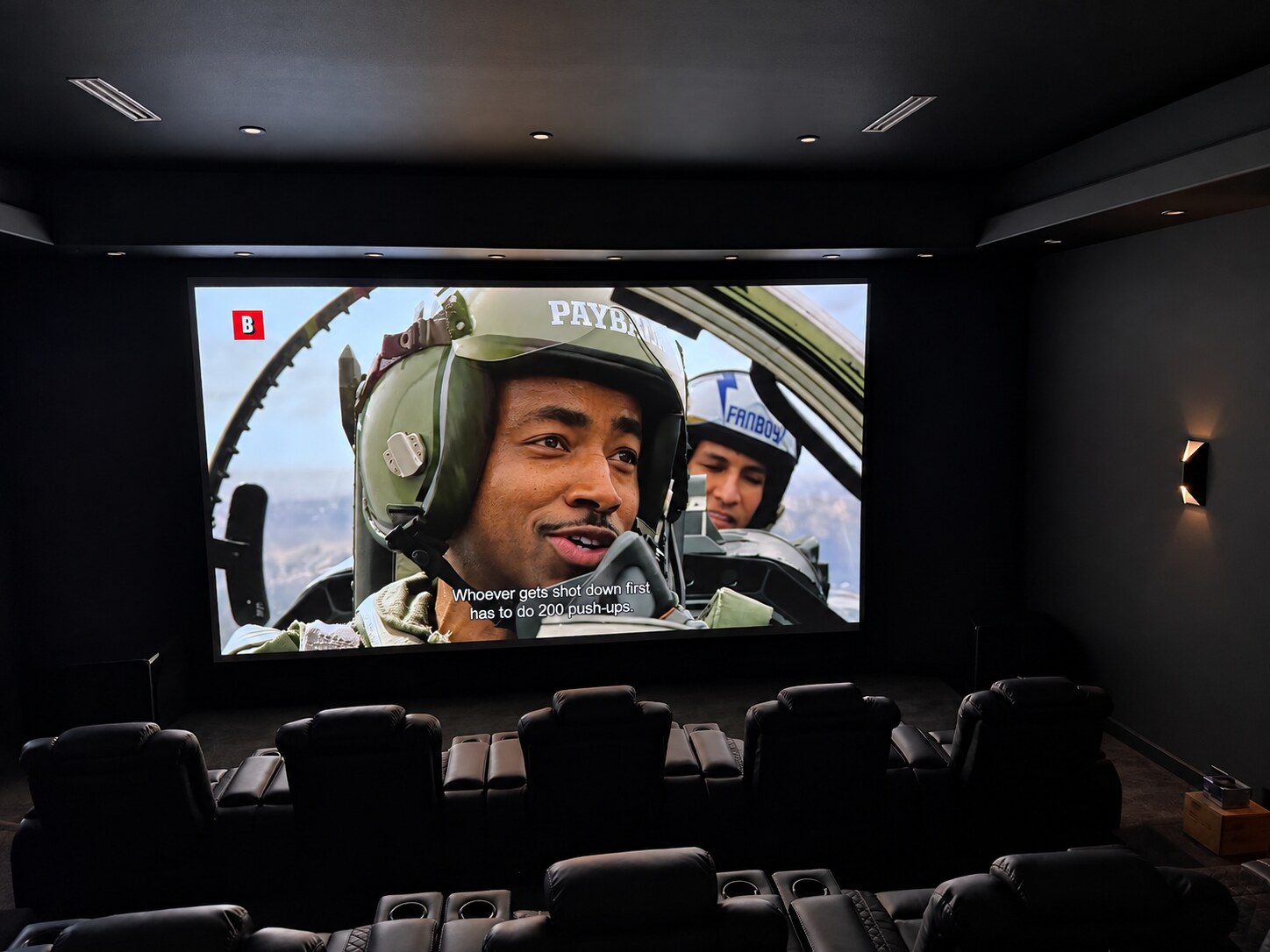 Home theater with tiered seating and a large screen